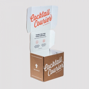 An open cardboard box with the text "Cocktail Courier" in red on the white inner flaps and "Cocktail Courier by Shakestir" on the brown outer sides. The well-designed packaging includes a thank you message and an arrow indicating the top side, showcasing thoughtful graphics throughout.