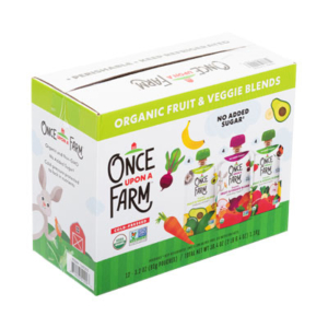 A package of Once Upon a Farm organic fruit and veggie blends is shown. The cardboard box features charming cartoon illustrations of a rabbit, fruit, and vegetables. Text on the packaging highlights "No Added Sugar" and "Cold-Pressed." The pack contains 12 individual pouches of blends.