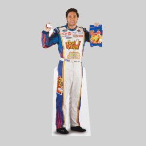 A man in a racing jumpsuit adorned with various sponsor logos is smiling and standing against a plain gray background. He is holding a hamburger with his right hand and a cardboard box of frozen fish fillets with sharp graphics in his left hand.