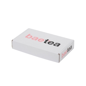 A rectangular white box with the word "baetea" printed on the top in pink and black letters. The box is plain, featuring sharp graphics and a minimalist design, resembling a sleek subscription box.