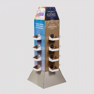 A hexagonal cardboard display stand featuring Christmas music albums. It has a brown and blue design with images of album covers, text promoting "Wow Hits 2015" and Chris Tomlin's "Adore: Christmas Songs of Worship," and multiple shelves holding CDs, perfect for holiday package displays.