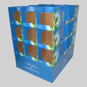 A blue cardboard retail display stand featuring multiple empty compartments for H2O+ sea-derived skincare products. The stand is branded with sharp graphics of fresh green leaves and water droplets, showcasing the H2O+ logo prominently displayed, creating an eye-catching package for shoppers.