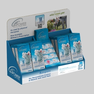 A display stand showcasing the Omron Electrotherapy Pain Relief device, neatly arranged in attractive packaging. The stand features multiple boxes of the device, promotional material, and an image of a person walking pain-free. Text highlights its use for muscle and joint pain without a prescription.