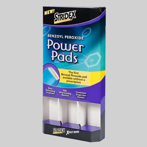 A box of Stridex Power Pads is shown on a gray background, with sharp graphics highlighting Benzoyl Peroxide as the active ingredient. The packaging promotes features like deep pore cleansing, killing acne-causing bacteria, and convenience in single-use packets.