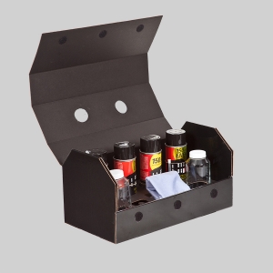 A black open box serves as the perfect packaging for various car care products, including bottles of cleaning solutions, a blue microfiber cloth, and an empty clear glass bottle. The box has a flap lid, and the interior is sectioned to hold the items securely.