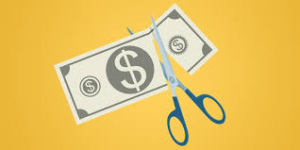 Illustration of a pair of blue scissors cutting a US dollar bill in half against a yellow background, symbolizing financial cuts or reduction in money. The sharp graphics provide a striking visual, reminiscent of the precision needed in packaging and shipping box designs.