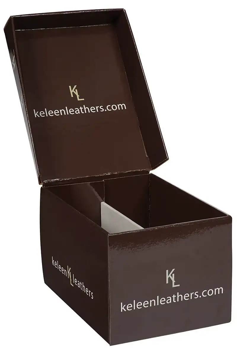 A photo of an open brown cardboard shipping container with sharp graphics featuring the text "keleenleathers.com" and "KL" logos printed on the inside of the lid and the sides. The lid is slightly tilted back, revealing the interior of the package.