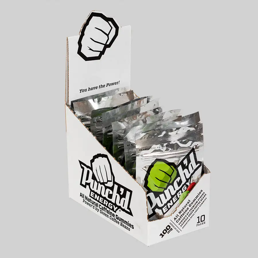 A display box of Punch'd Energy Gummies with silver packets inside. The cardboard box features a fist logo and the text "Punch'd ENERGY" along with "You have the Power!" Each packet advertises 10mg of natural caffeine per gummy and totals 10 pieces per pack.