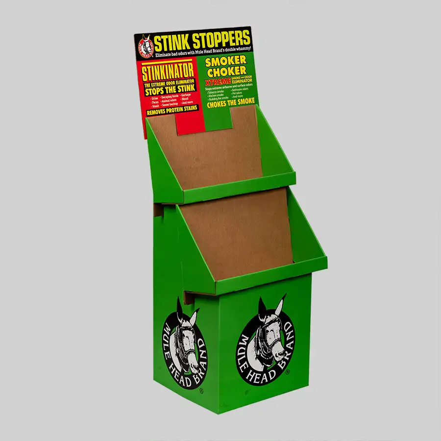 A green, two-tiered cardboard display stand with compartments for holding products. The sign at the top reads "Stink Stoppers" and describes the items "StinkinAtor" and "Smoker Choker." The packaging features the Mule Head Brand logo.