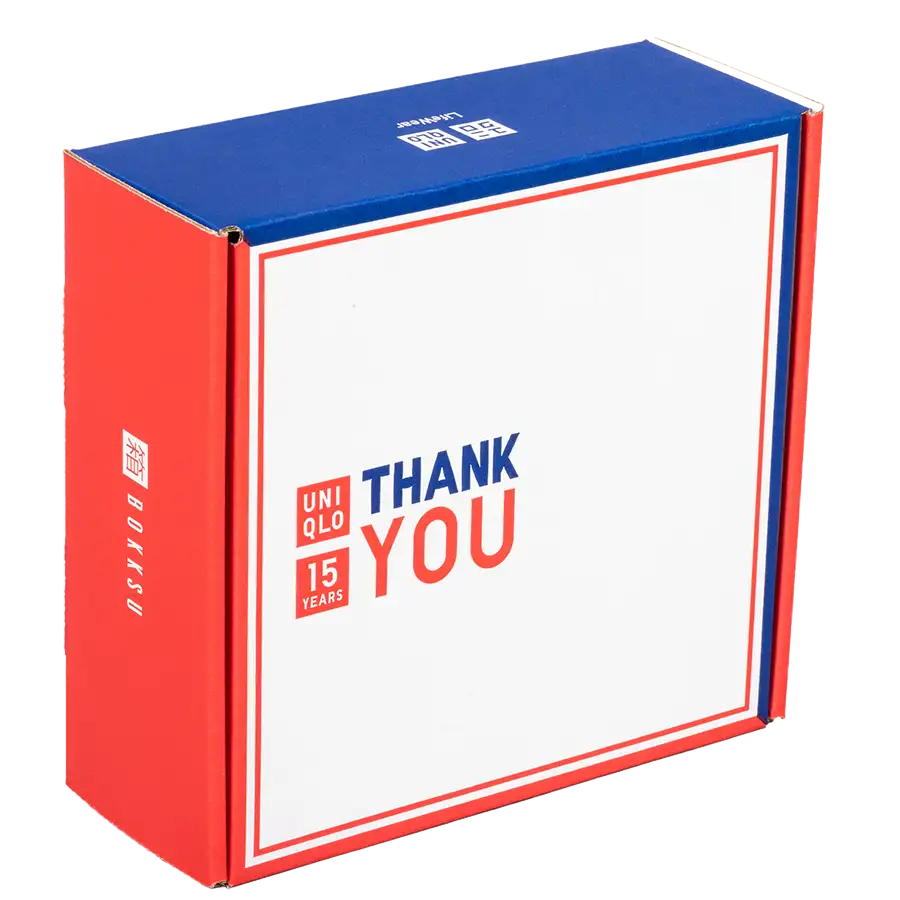 A rectangular packaging box with a blue top and red sides features the text "UNIQLO THANK YOU 15 YEARS" on the front in red and blue. The design celebrates Uniqlo's 15-year anniversary in collaboration with Bokksu.